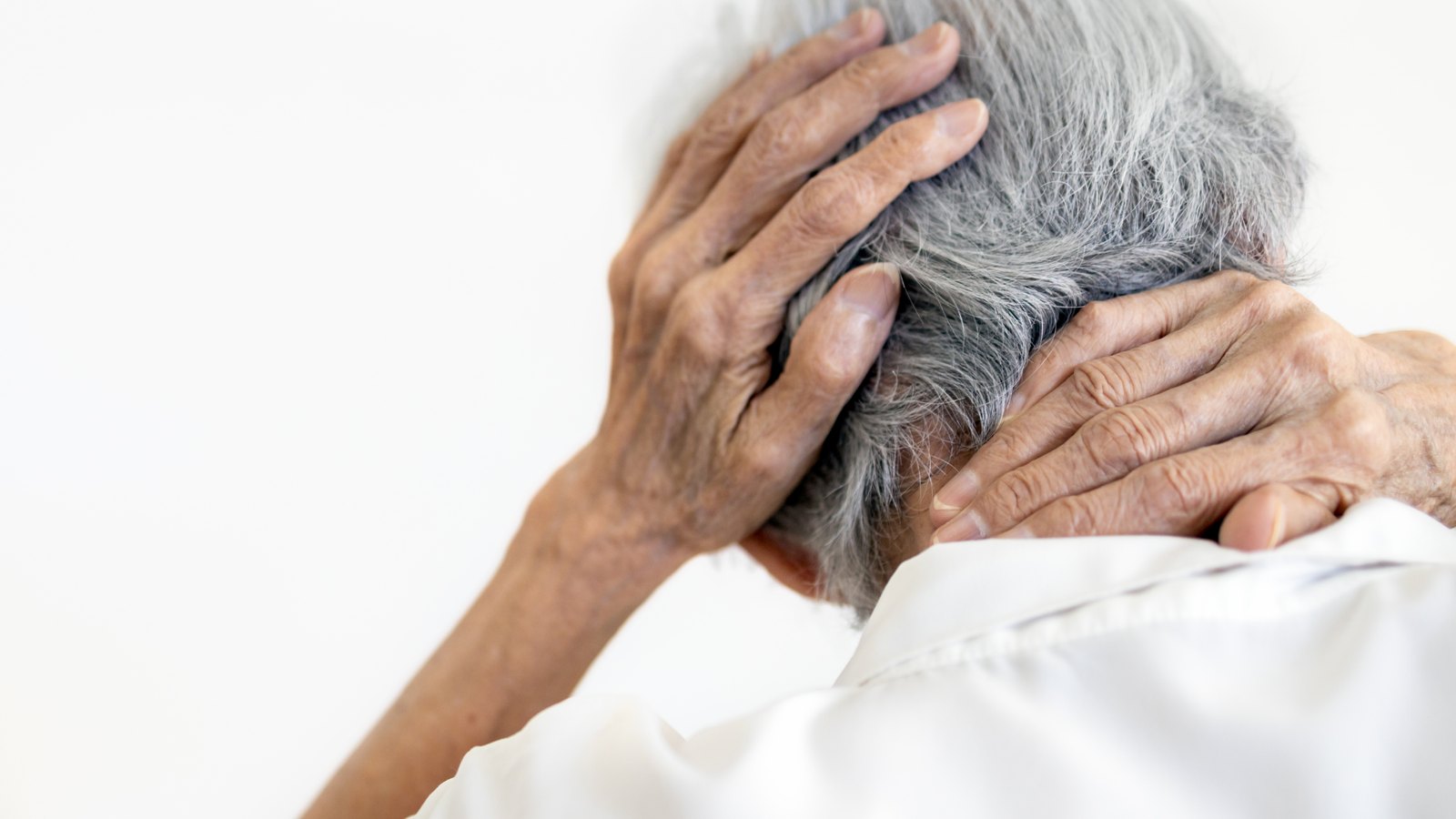 Older person holding their head and neck