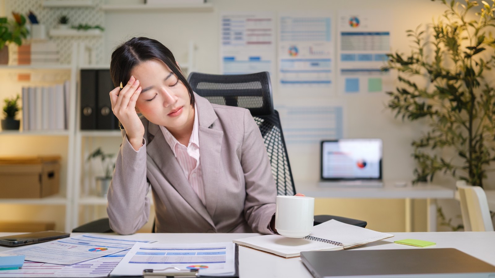 Woman at her office desk with a headache