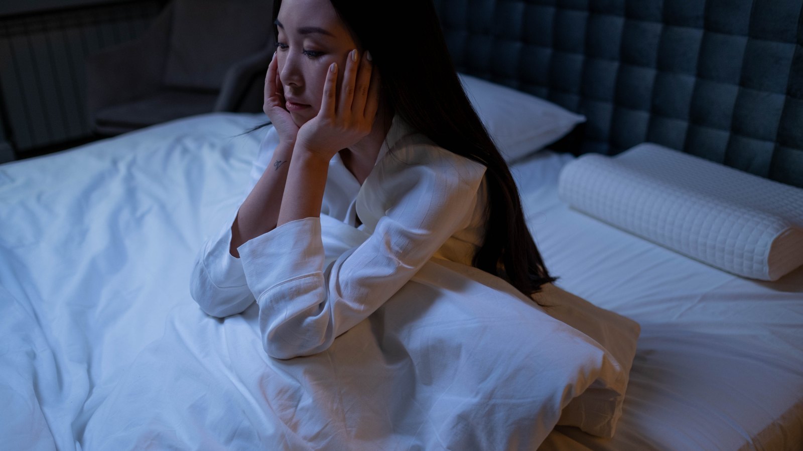 Woman sitting up awake in bed at night