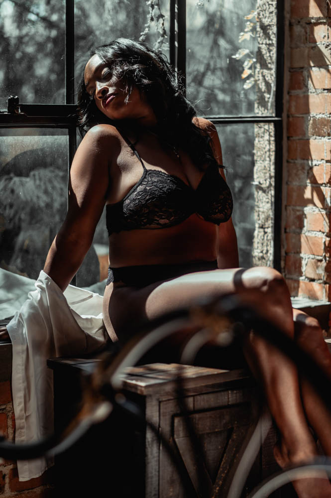 Woman sitting in window, loft style, wearing a white button up shirt and black lingerie