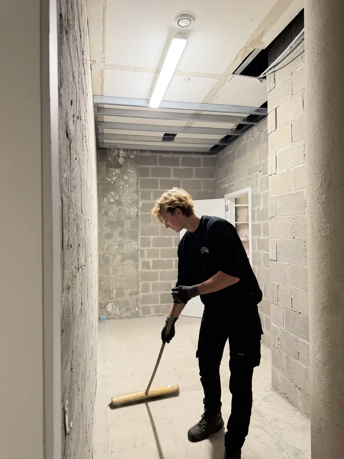 Medewerker van Damagmee veegt een leeggemaakte ruimte bezemschoon