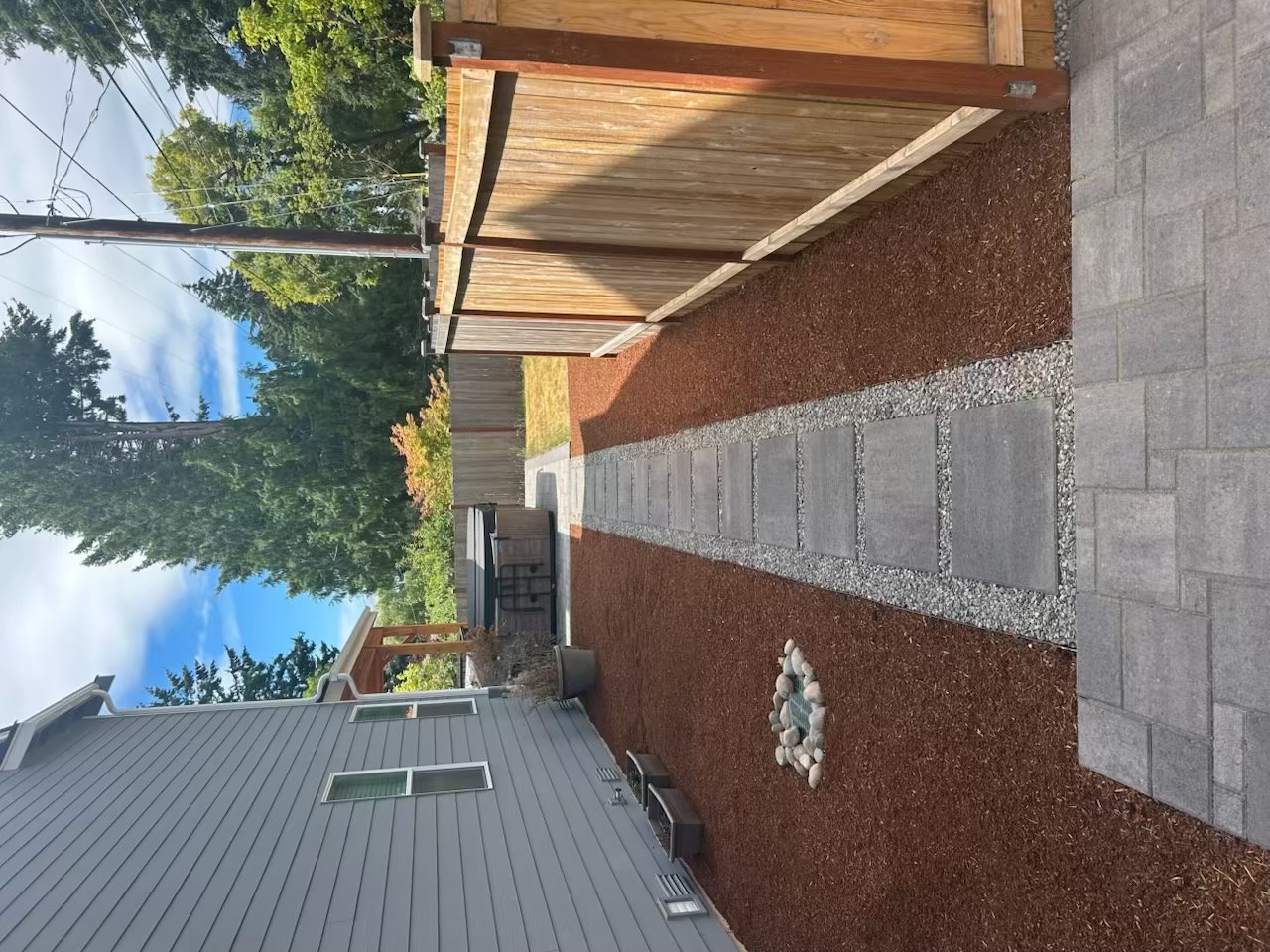 Rectangular stepping stones in gravel between mulched beds and a wood fence