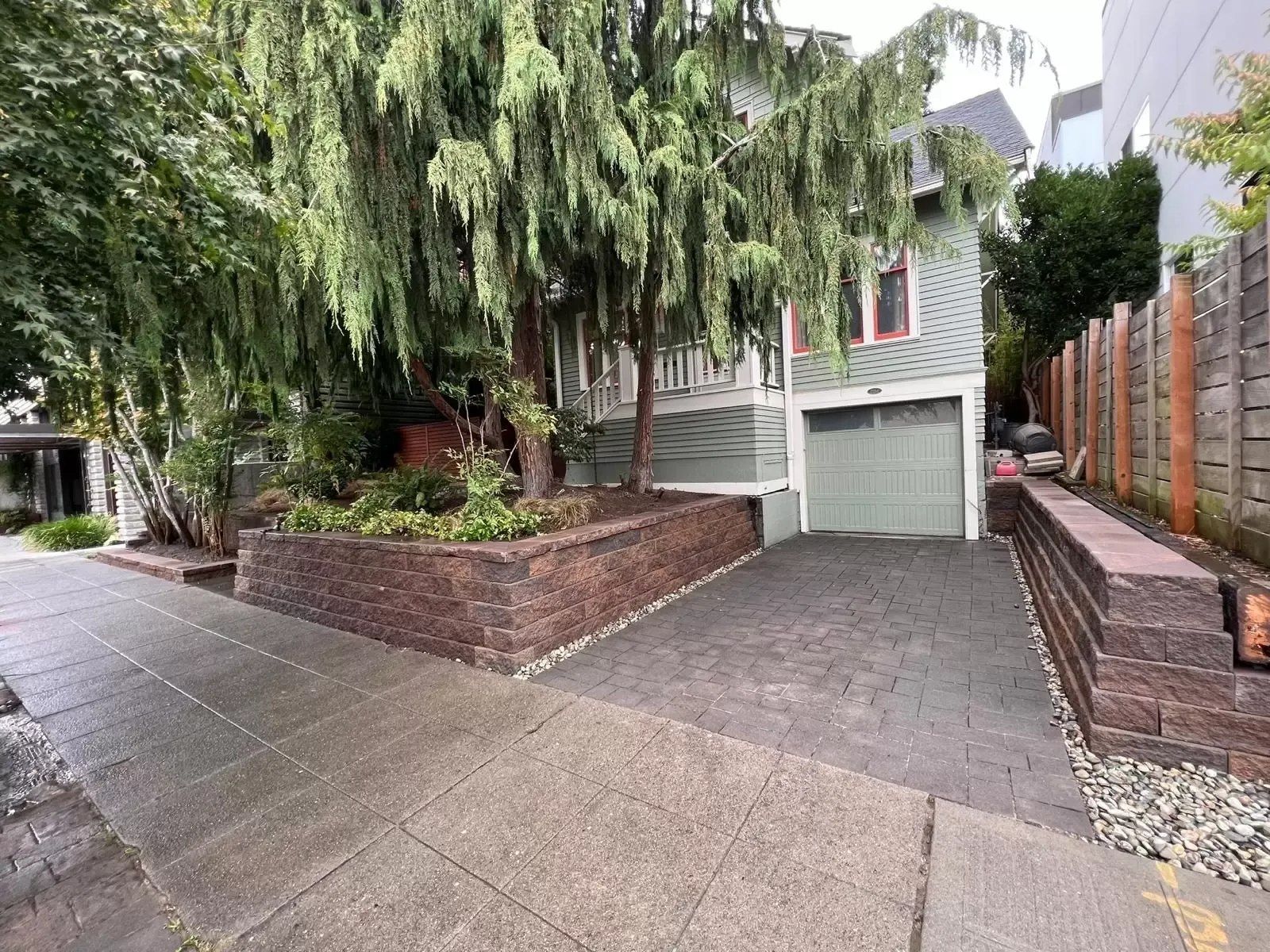 Gray paver driveway between block retaining walls in front of a garage