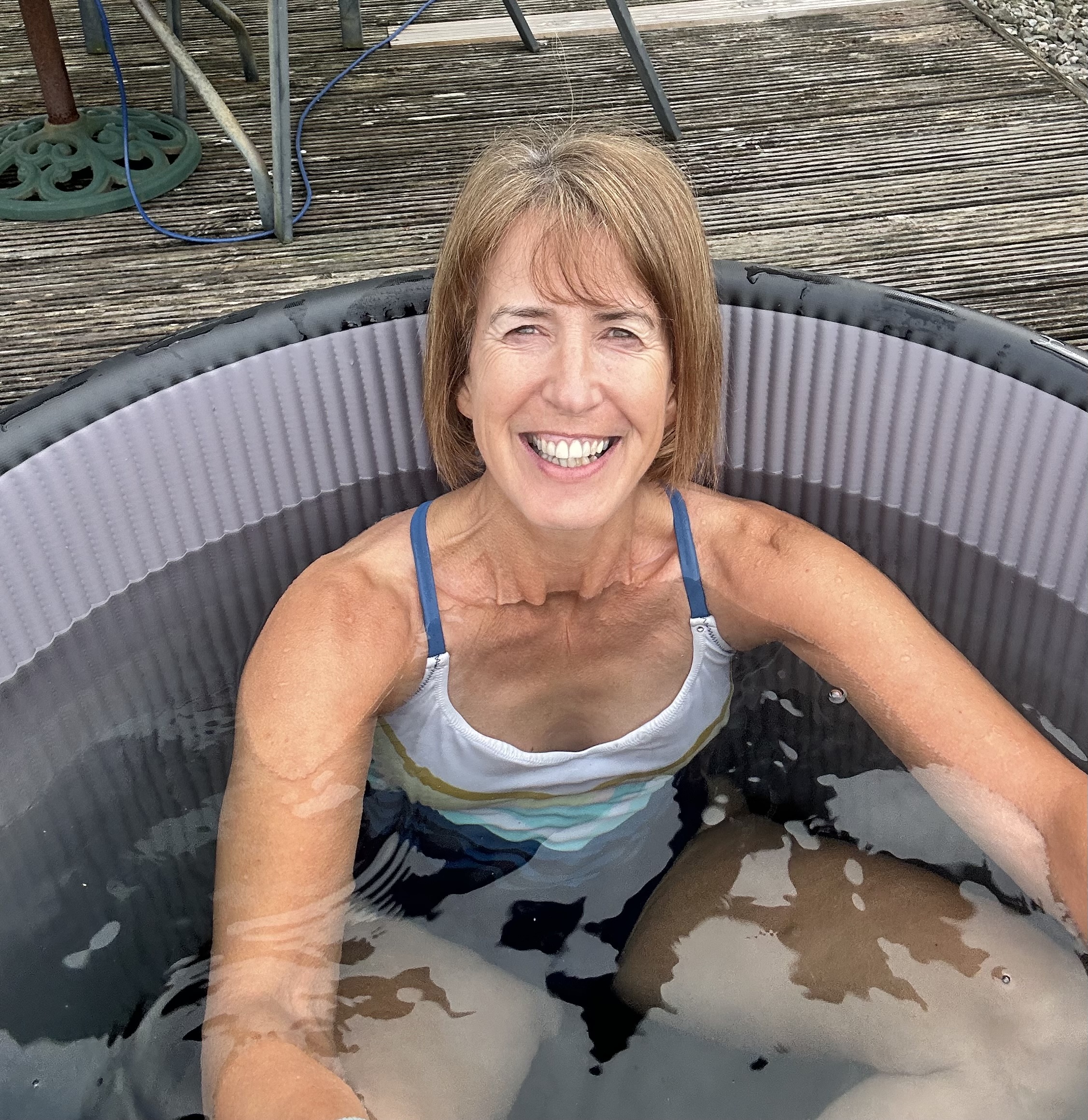 Liz in cold plunge tub, smiling in the sunshine