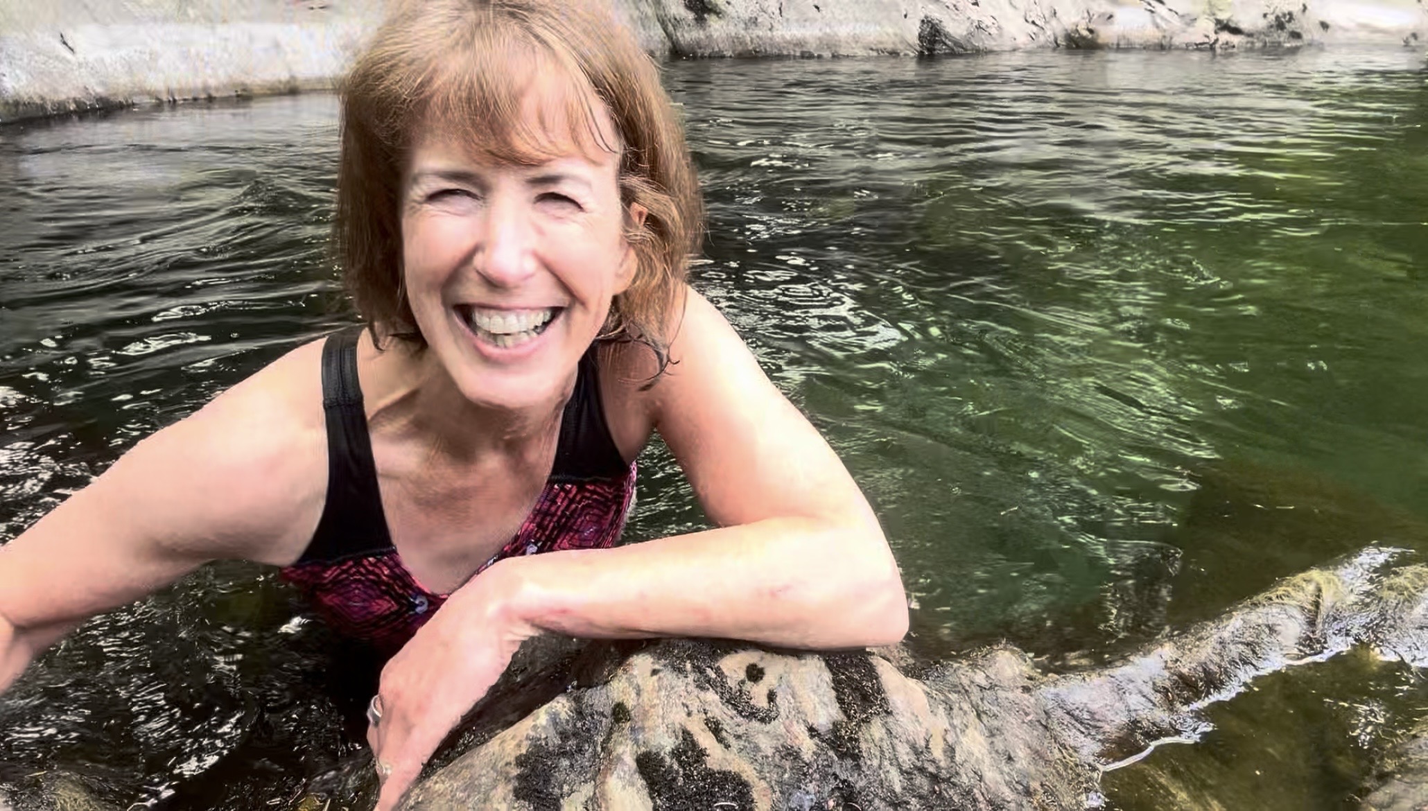 Liz in a rocky plunge pool, laughing
