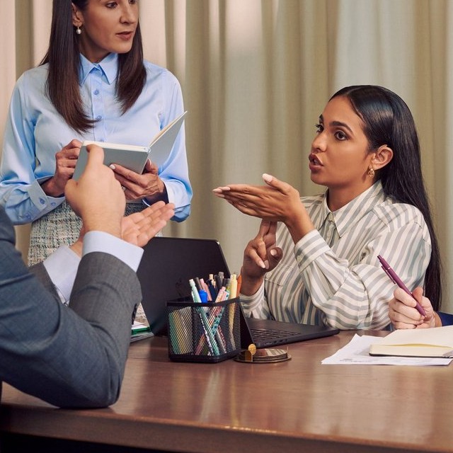 Staff members in a group training session, one signing as a colleague holds a workbook