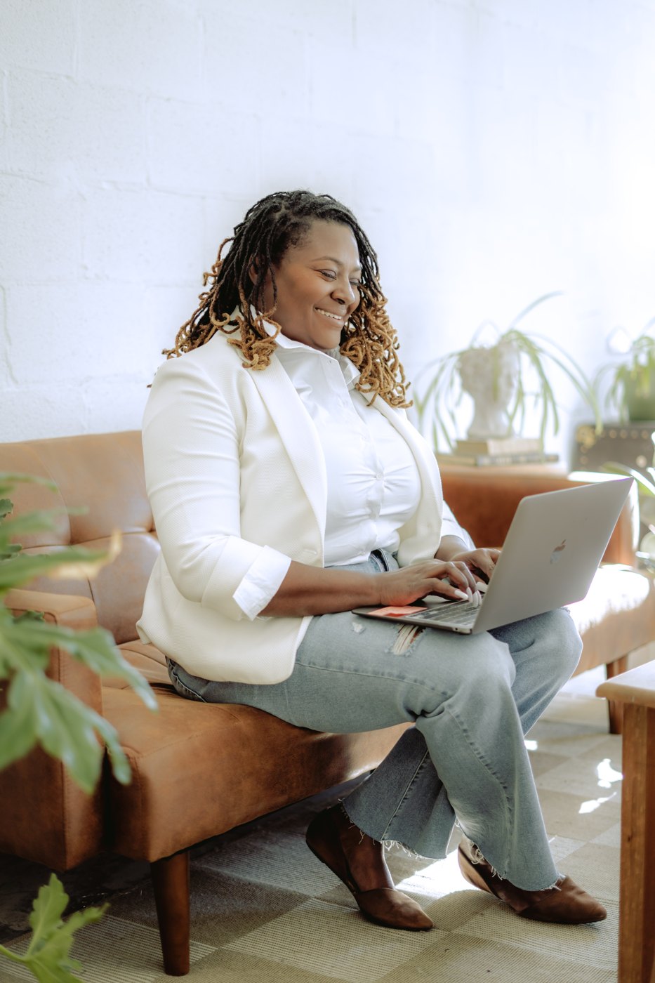 Starr Clinton working on her laptop on a leather couch