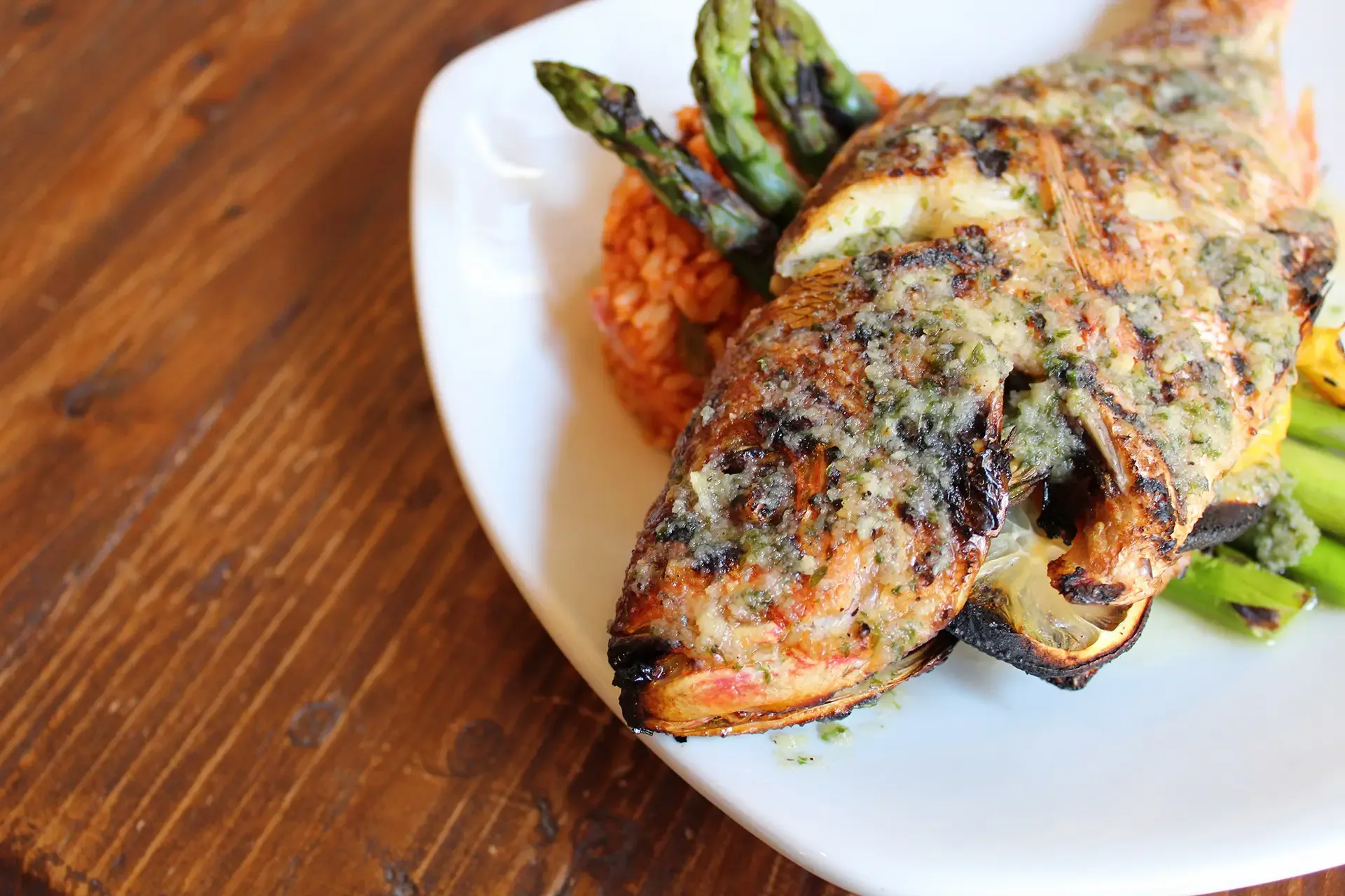 Grilled whole fish served with seasoned rice, roasted asparagus, and vegetables at Oyster House.