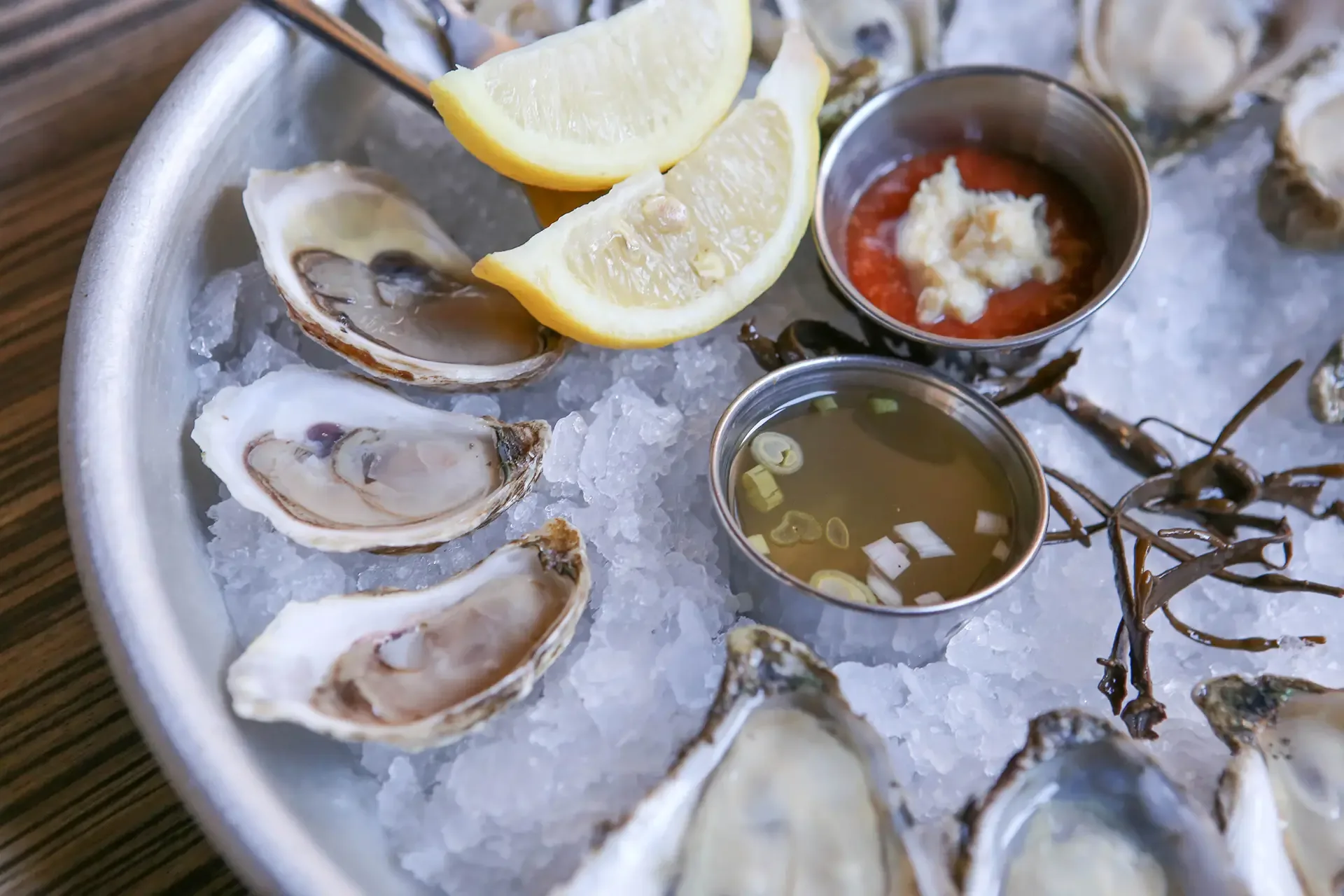 Fresh raw oysters served on a bed of ice with lemon wedges and dipping sauces at Oyster House.