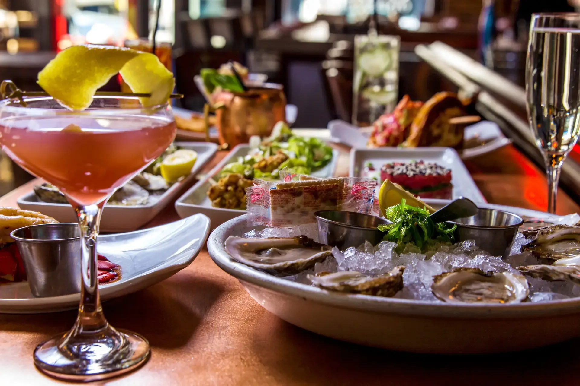 Elegant seafood spread at Oyster House featuring fresh oysters on ice, gourmet appetizers, and signature cocktails served in a vibrant dining setting.
