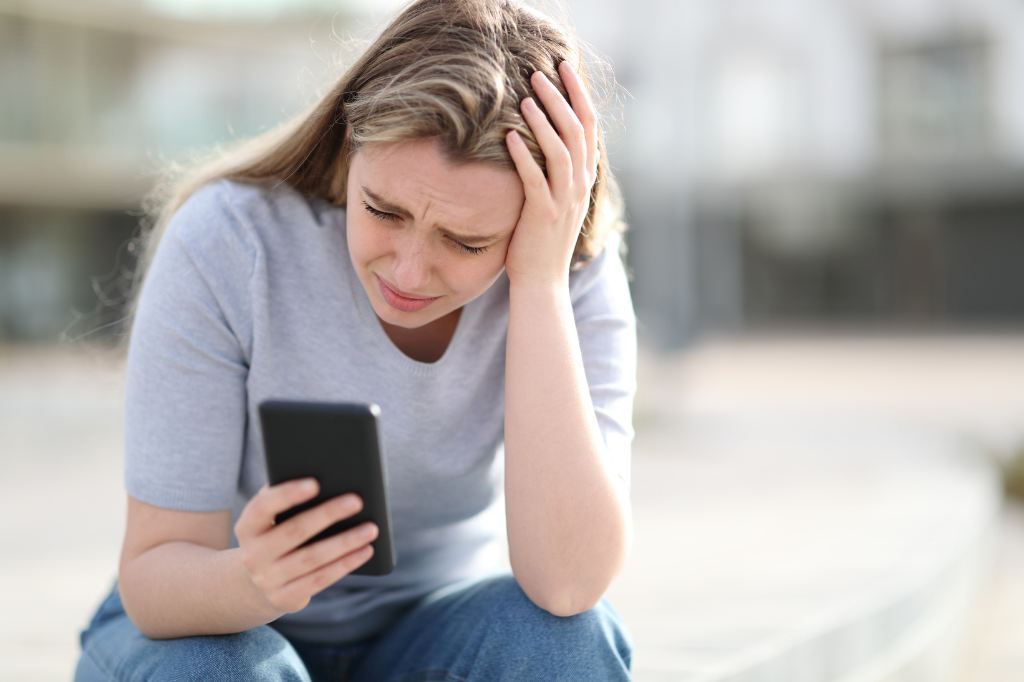A sad tween or teen girl reads tragic news on her cell phone