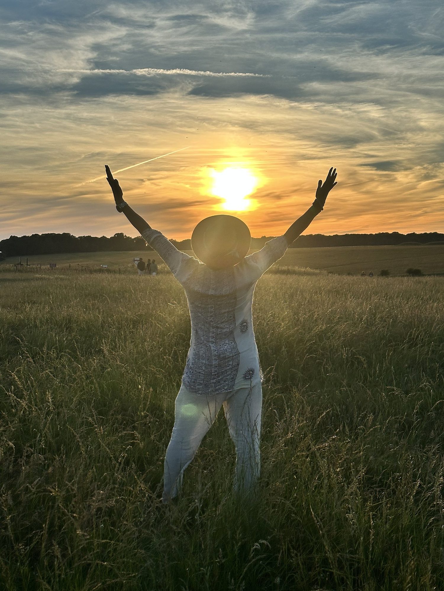 A figure in a field at sunset, arms raised