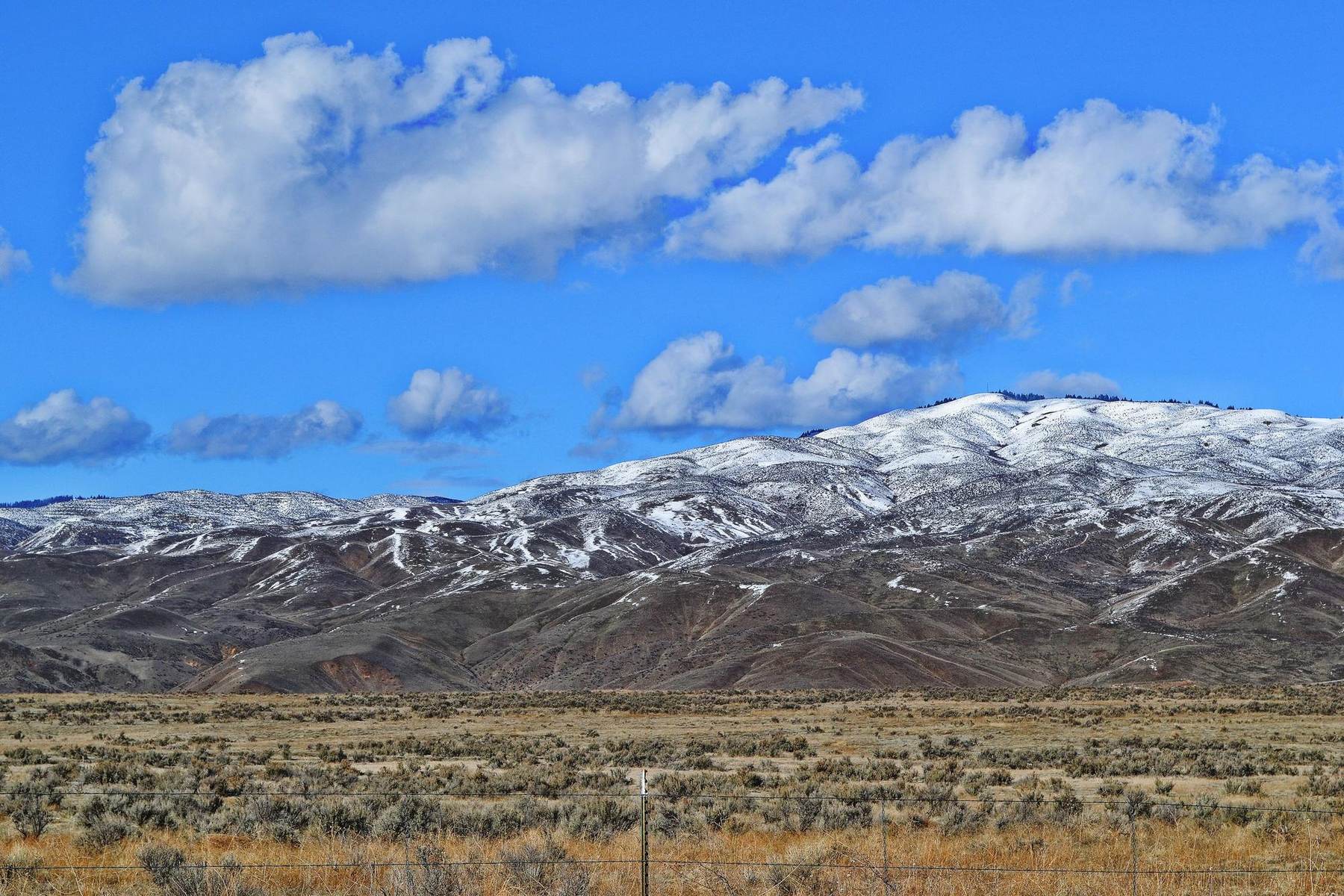 Snow-covered mountain range rising above a sagebrush valley