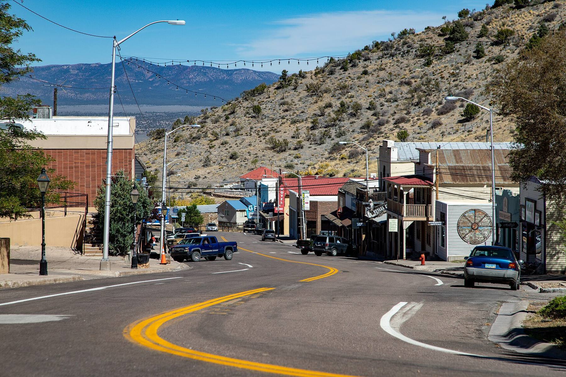 Main Street in Pioche, Nevada, curving past historic storefronts below a sagebrush hillside