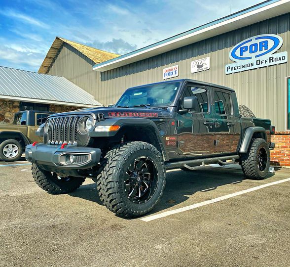 Lifted Jeep Gladiator on black off-road wheels outside Precision Off Road in Leesburg