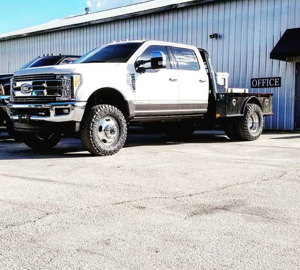 White Ford Super Duty flatbed work truck parked at the Precision Off Road shop