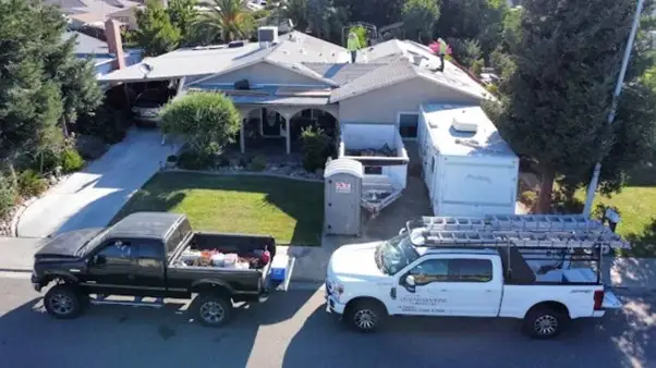New dark gray asphalt shingle roof on modern home in Modesto CA with green trees and clear blue sky. Quality craftsmanship.