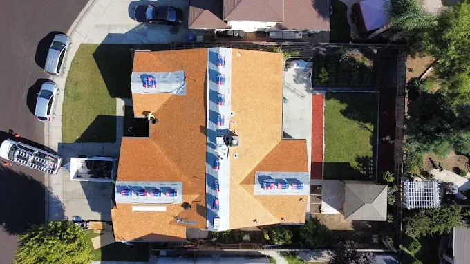 Recently replaced durable asphalt shingle roof on a suburban home in Modesto CA with lush lawns and clear sky