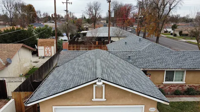 Completed seamless aluminum gutter installation on a residential roof in Modesto with clean cuts and secure downspouts