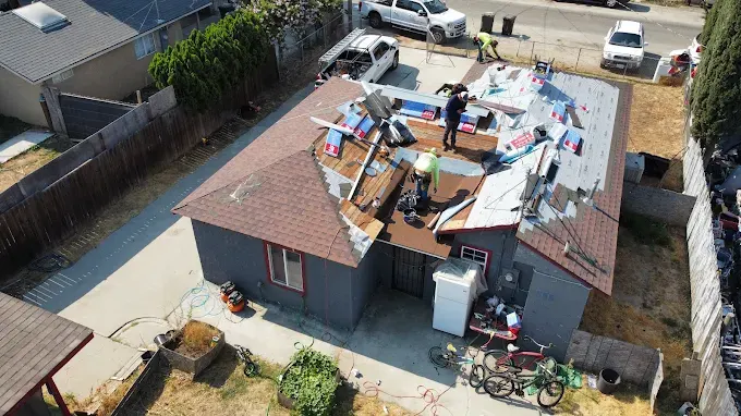 Completed flat roof in Modesto CA with reflective membrane, sealed edges, roofing tools, and surrounding modern buildings