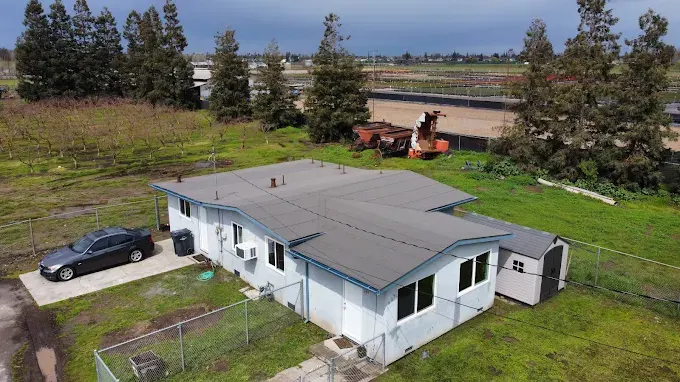 Freshly completed seamless flat roof on a commercial building in Modesto CA with green landscaping and cityscape background
