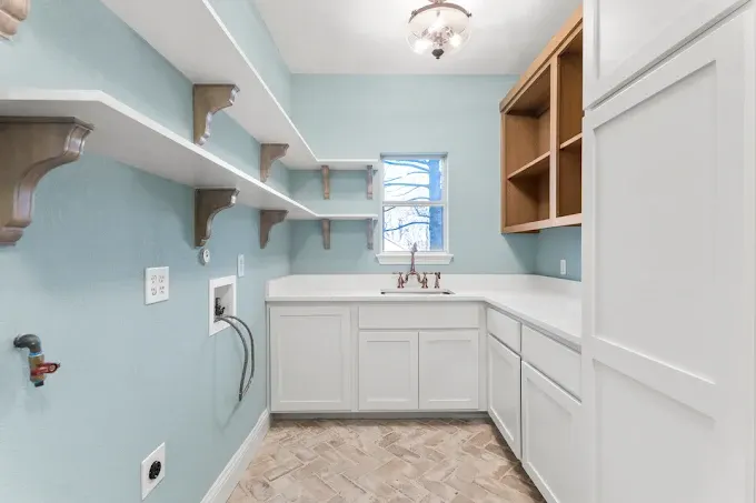Remodeled Austin Texas kitchen with quartz countertops stainless steel appliances wooden cabinets large island pendant lighting natural sunlight modern backsplash open living area hardwood floors