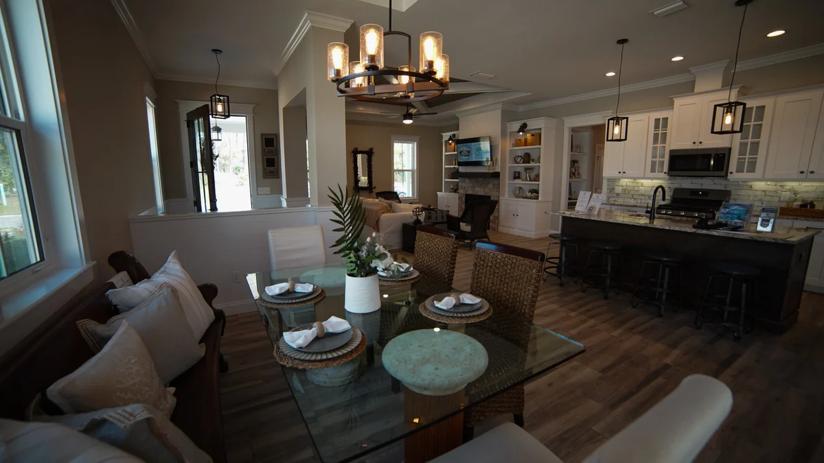 A wide view of an open-concept home featuring a modern dining area, a cozy living room, and a bright kitchen with an island.