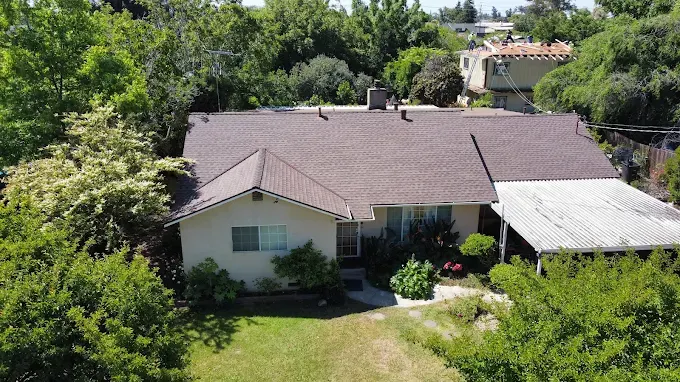 Newly installed seamless aluminum gutters with matching downspouts on a modern home in Modesto California with landscaped yard and sunny weather