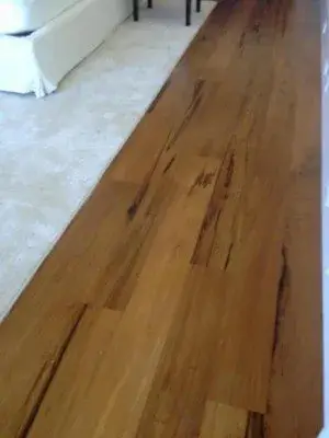Hardwood floor transition strip installation in a coastal decor setting with rich tones and natural light.
