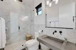 Completed modern bathroom vanity in Austin with marble countertop dark wood cabinet chrome fixtures natural light
