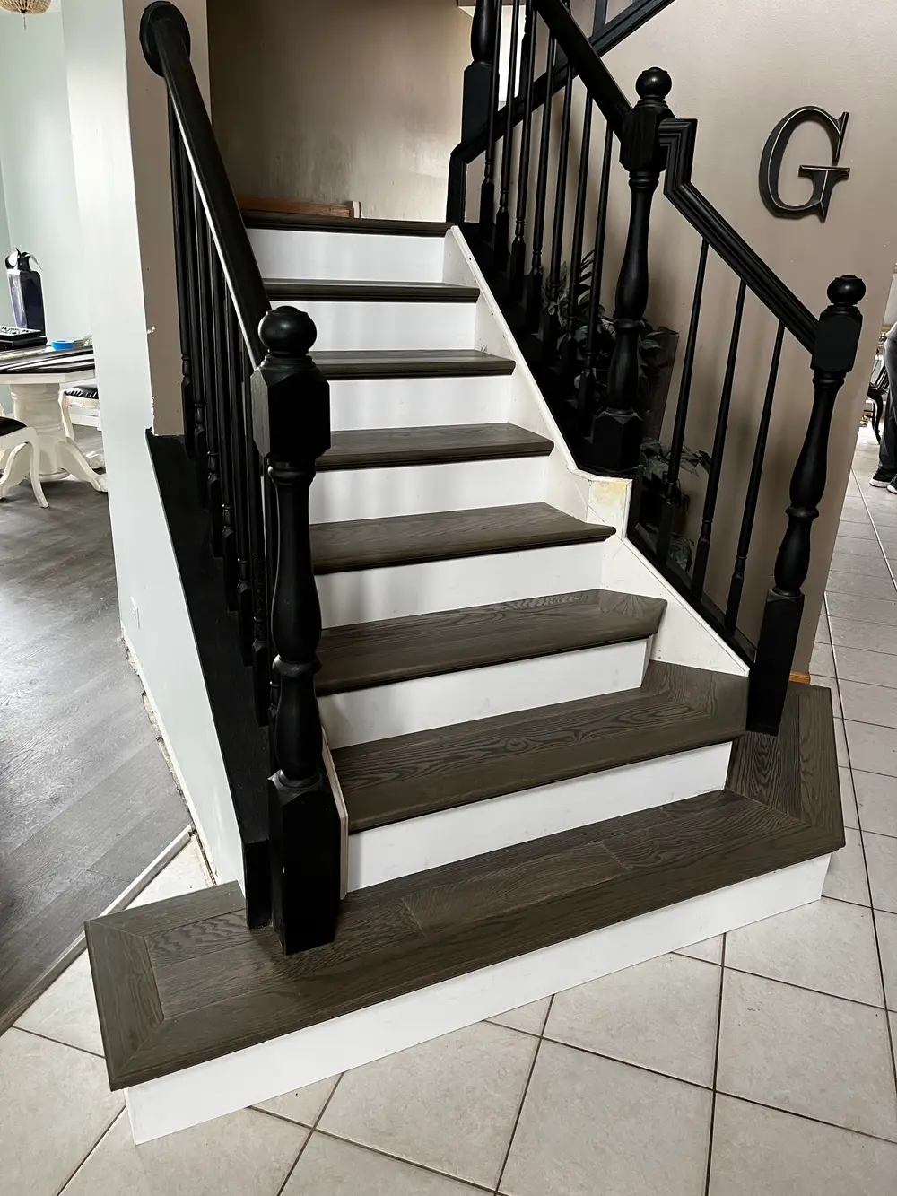 A beautifully renovated staircase featuring dark wood treads, white risers, and a sleek black balustrade in a modern home.