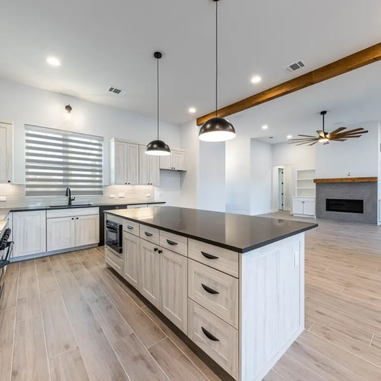 Finished modern Austin kitchen with warm wood cabinets marble island gold fixtures large windows scenic view polished hardwood