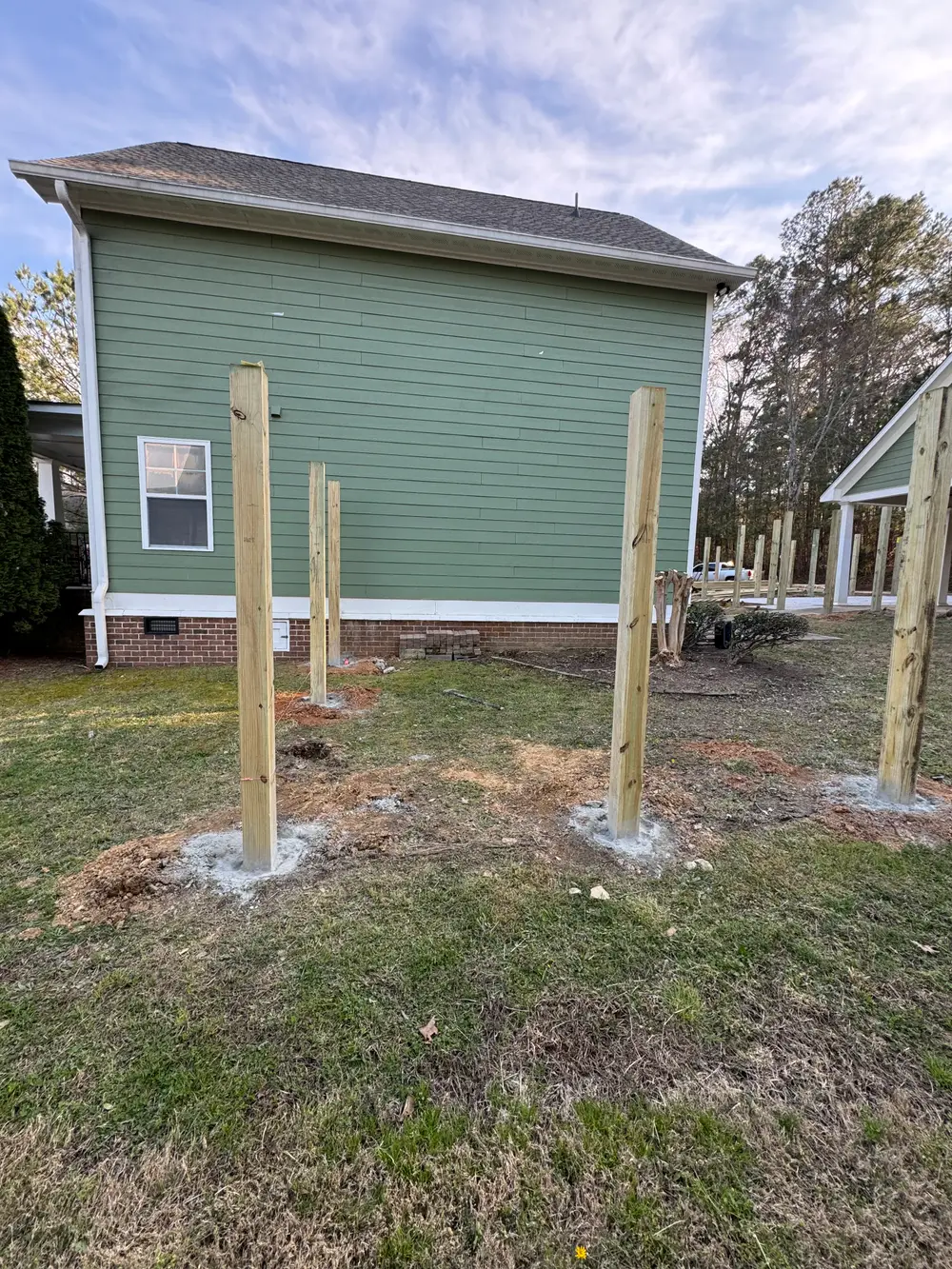Completed wooden picket fence in Tunnel Hill GA with lush grass, flowers, and clear blue sky, showcasing craftsmanship.