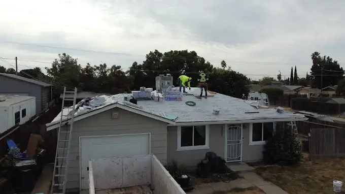Close-up of a new rubber pipe boot installed on a residential roof in Modesto California, with shingles and blue sky background