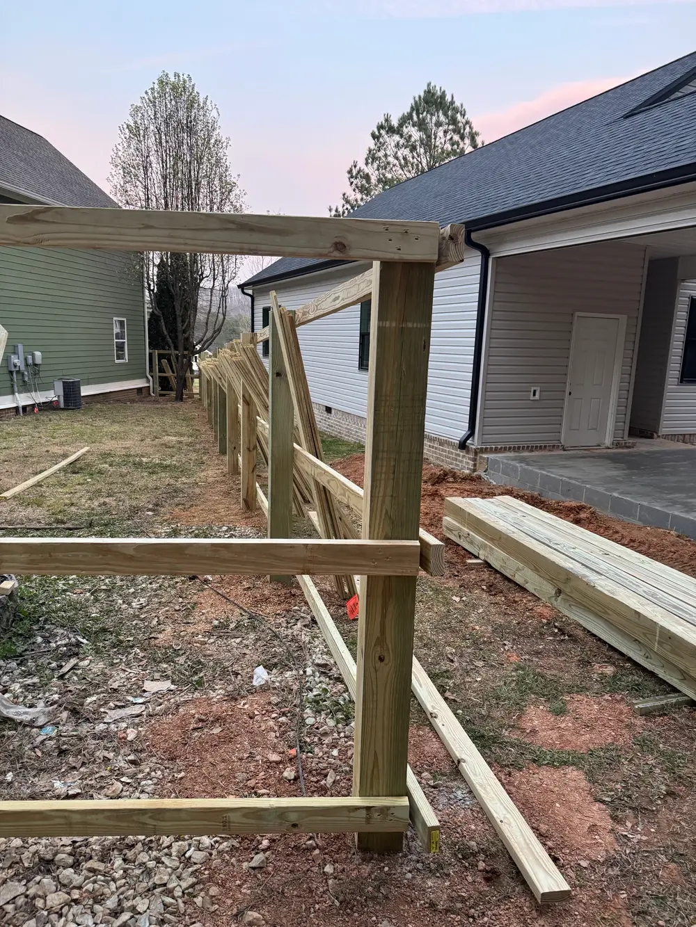 Beautiful wooden fence in LaFayette GA, showcasing rich wood tones, lush lawn, and serene blue sky.
