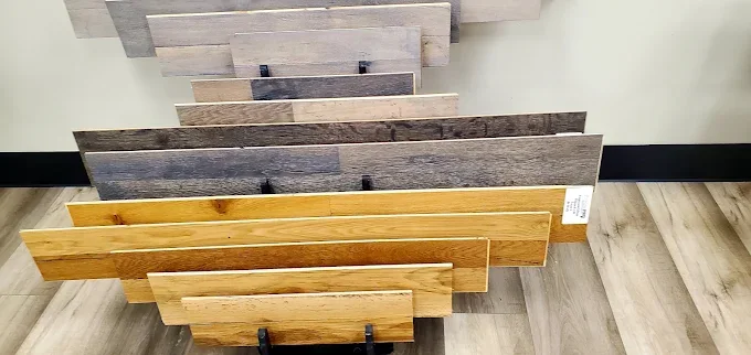 A showroom display features a wide range of wood flooring samples, from light oak to dark gray, for home renovation.