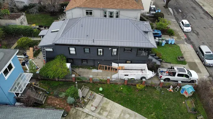 Clean, shiny green gutters on a suburban home with lush landscaping, bright sunlight, and a tidy yard.