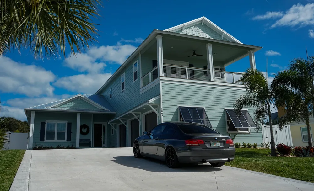 New construction painting of a modern home in New Smyrna Beach with vibrant coastal colors and lush greenery.