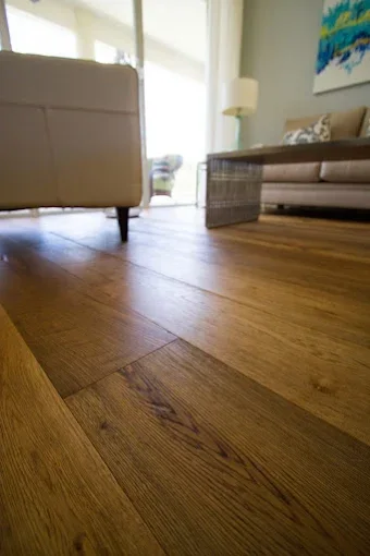 Completed wood flooring in a Naples FL living room, showcasing rich tones, natural light, and elegant decor.