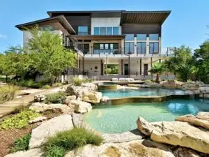 Completed cedar deck with wrought-iron railings and native plants in a Texas landscape showcasing craftsmanship in Austin