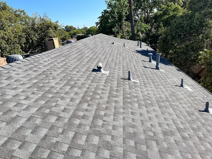 Close-up of a well-installed weather-resistant metal chimney flashing around a brick chimney in Modesto California with a suburban roof background