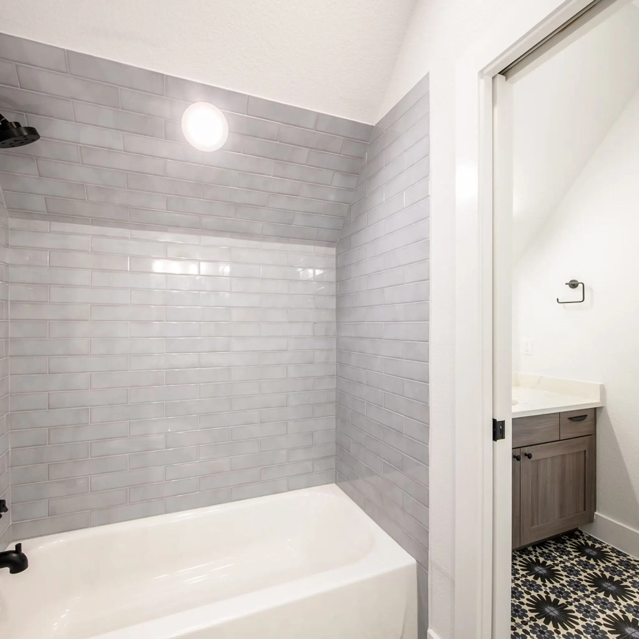 Beautiful modern bathroom with custom mosaic tile shower, sleek glass doors, chrome fixtures, and neutral tones in Austin Texas
