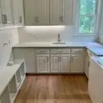 Freshly renovated kitchen cabinet interior with warm wood tones, sleek modern doors, granite countertops, stainless steel appliances, and subtle lighting