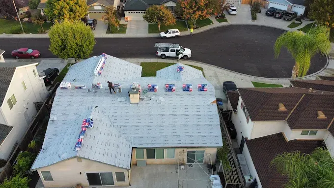 Recently installed shiny metal roof on modern home in Modesto with lush yard and bright daylight