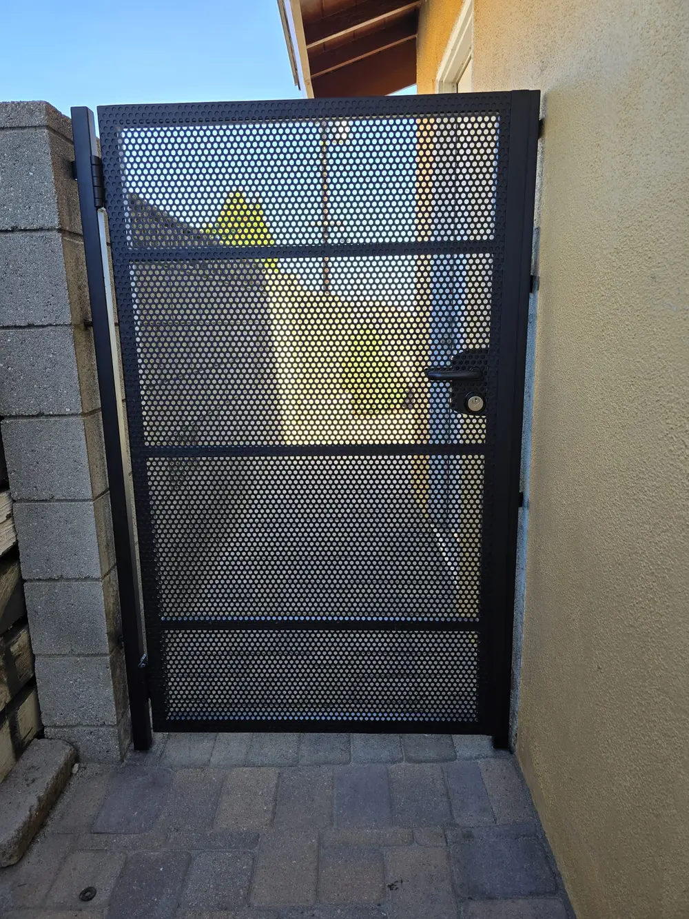 Custom wrought iron gate in Los Angeles surrounded by vibrant flowers and lush greenery under a clear blue sky