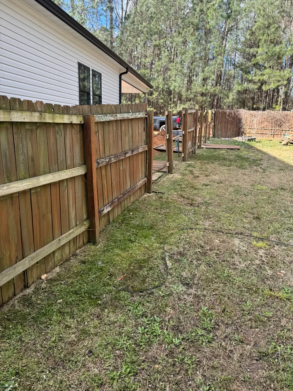 Completed fence repair in Cohutta GA with rich brown stains, vibrant yard, and serene sunlight filtering through trees.