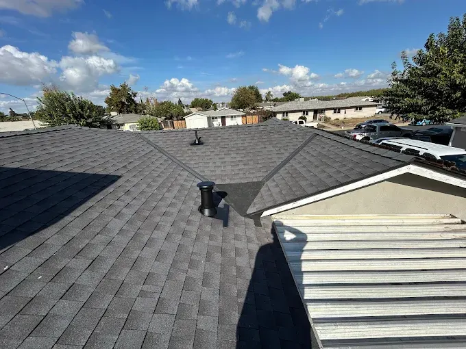 Recently replaced asphalt shingle roof on a suburban home in Modesto CA with lush greenery and neighboring homes.