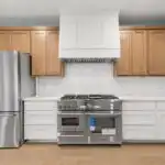 High-end custom wooden kitchen cabinet with intricate detailing in a modern Austin upscale kitchen featuring marble countertops and stainless steel appliances