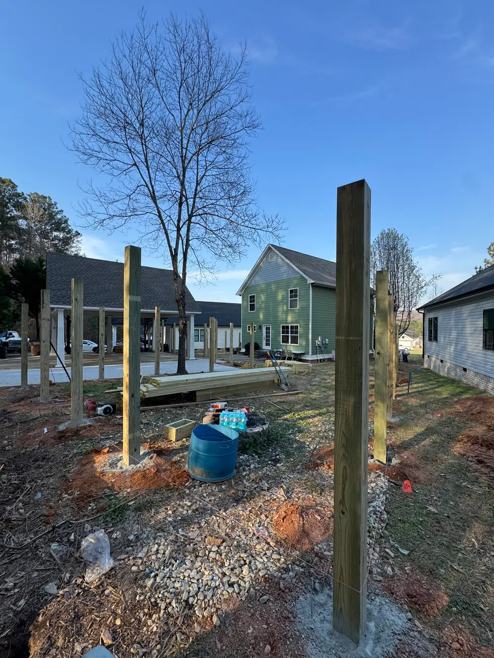 Completed wooden fence in Piedmont AL with natural stain, surrounded by lush grass and vibrant wildflowers.