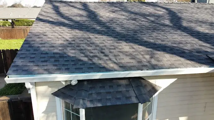Beautiful suburban home in Modesto with a newly installed durable roof, neat landscaping, and surrounding trees under bright sun